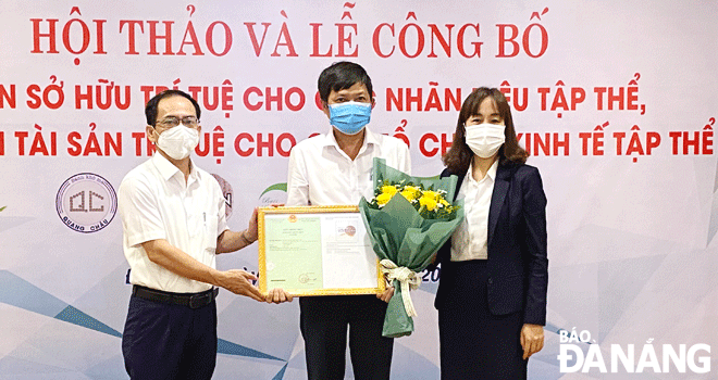 Mr Le Duc Vien (left), Director of the municipal Department of Science and Technology awarded the certificate of intellectual property for agricultural products in Hoa Vang District. Photo: M.QUE