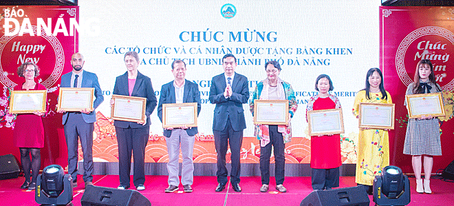 Chairman of the Da Nang People's Committee Le Trung Chinh (mid) presents a certificate of merit to Ms Cécile Le Pham (fourth, right), Vice President of French Association for Orphans and Destitute Children in Viet Nam (ASSORV) and other organizations, individuals on the occasion of meeting foreigners in Lunar New Year 2021. Photo: Reporter.