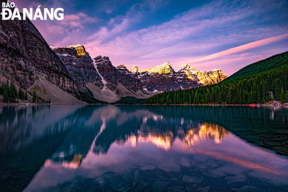 Moraine Lake is considered the most beautiful lake in the Banff National Park. The first glimmering rays of sunlight shine through the snowy mountains peaks create a golden colour, reflecting and sparkling at emerald water lake.