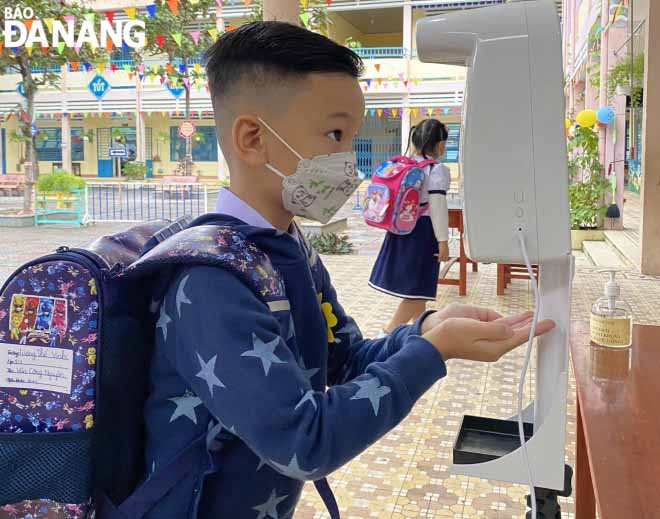 Students in grade 1 of the Ngo May Primary School in Son Tra District are required to check their body temperatures with an automatic body temperature monitoring device which is installed at the entrance gate to school.