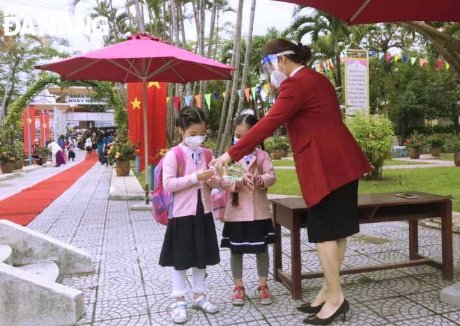 The Be Van Dan Primary School’s Year 1 students are guided to disinfect their hands before entering classrooms