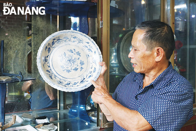 Mr. Nguyen Van Chin and his large unique porcelain plate made by Vietnamese people. Photo: TIEU YEN