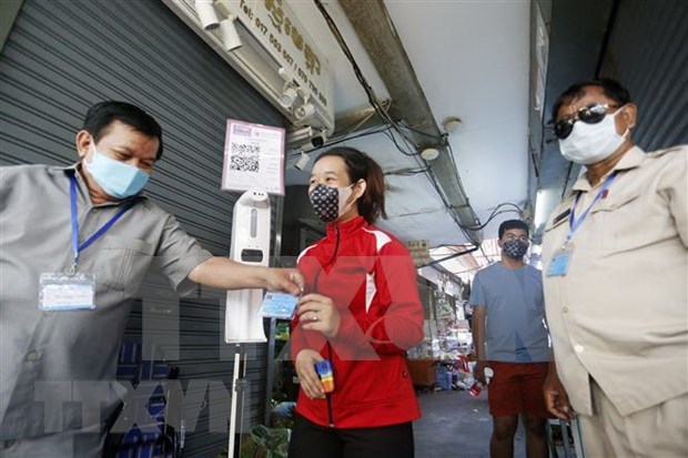 Market guards inspect a shopper's COVID-19 vaccination card at an entrance in Phnom Penh, Cambodia in October 2021. (Photo: Xinhua/VNA)