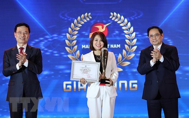 Prime Minister Pham Minh Chinh (right) and Minister of Information and Communications Nguyen Manh Hung (left) present the gold prize to a winner. (Photo: VNA)