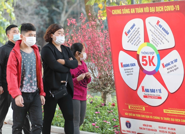 A family in Hà Nội passed by a Health Ministry's 5K message panel in Hoàn Kiếm Lake area during Tết (Lunar New Year) holiday of 2021. The health ministry has proposed stopping all entertainment activities during the coming Tết holidays. — VNA/VNS Photo