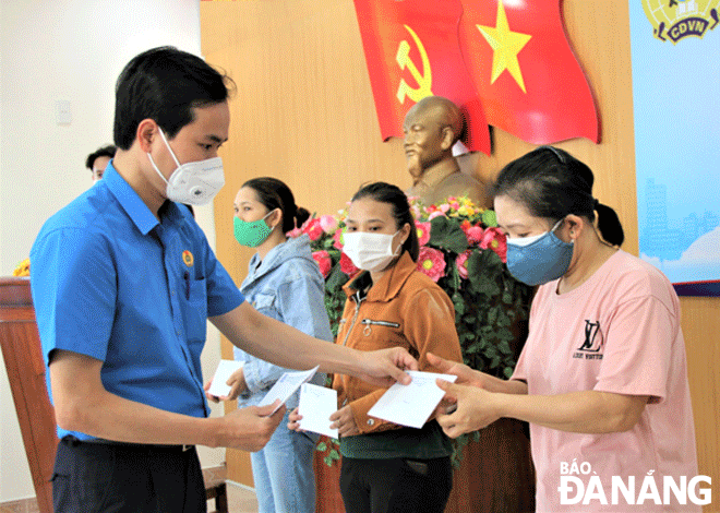Chủ tịch Liên đoàn Lao động thành phố Nguyễn Duy Minh (bìa trái) trao hỗ trợ cho đoàn viên tại quận Hải Châu  bị ảnh hưởng bởi Covid-19. Ảnh: L.PHƯƠNG