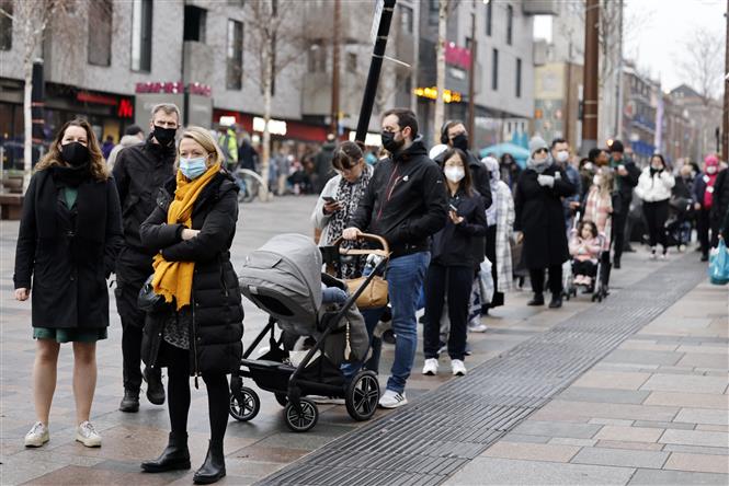 Người dân xếp hàng chờ tiêm vaccine phòng COVID-19 tại London, Anh ngày 18/12/2021. Ảnh: AFP/TTXVN