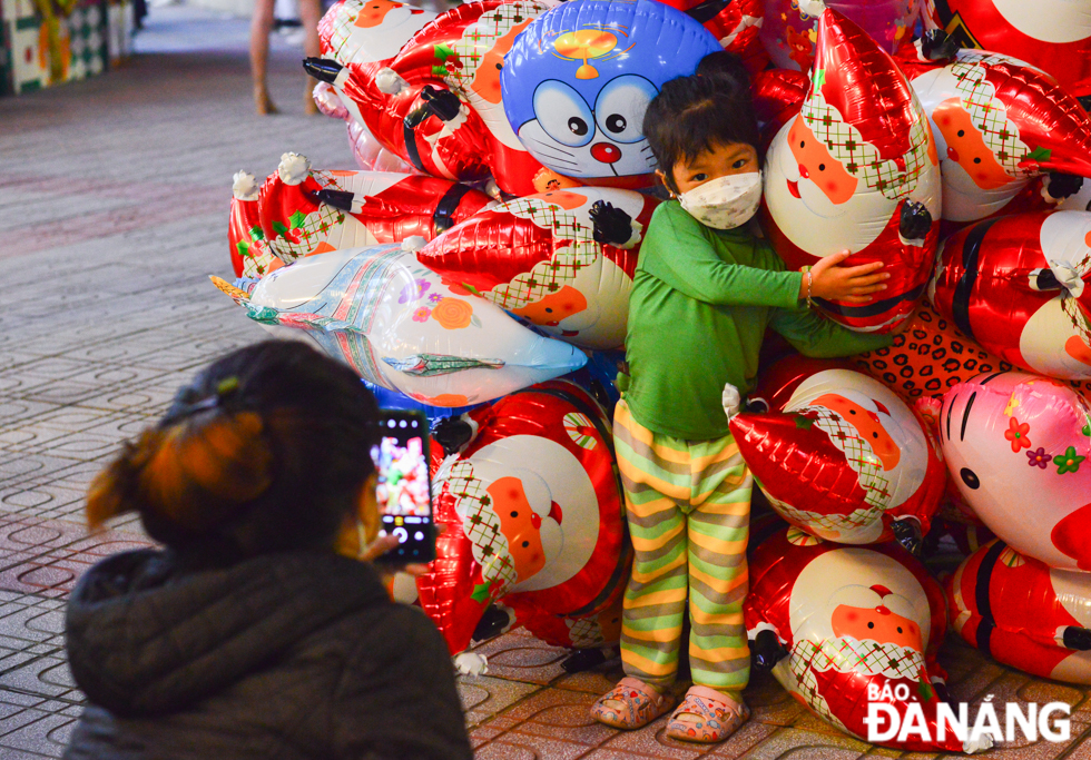 A child poses for a photo with a bunch of Christmas balloons.