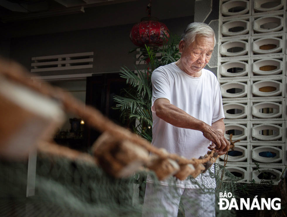 Ông Phạm Văn Liễn cột phao gỗ vào lưới. Nghề biển ở Mân Thái đã theo bao đời từ già đến trẻ vươn khơi xa.