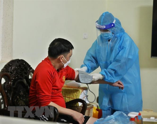 Nhân viên y tế đến theo dõi, kiểm tra sức khỏe cho 7 bệnh nhân F0 trong 1 gia đình tại nhà (xã Tam Hiệp, huyện Thanh Trì). (Ảnh: Minh Quyết/TTXVN)