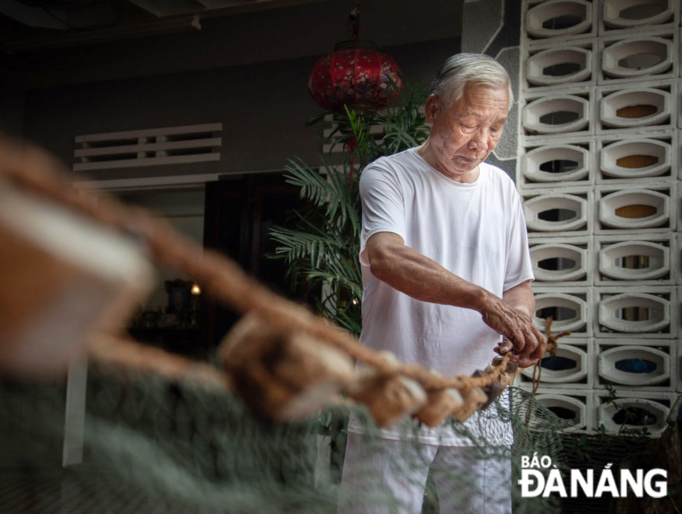 Mr. Pham Van Lien ties a wooden buoy to the net. The fishing craft in Man Thai has followed by many generations.