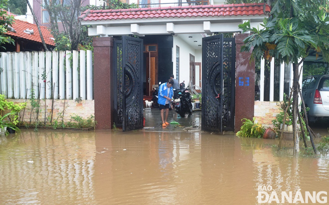 Một hộ dân ở tuyến đường Lương Hữu Khánh đang đẩy bùn non và chùi rửa sân nhà sau khi bị ngập nước.