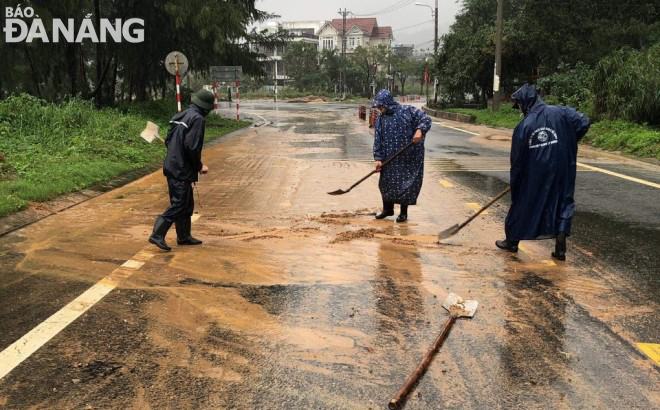 Công nhân Công ty CP Cầu đường Đà Nẵng đang xúc dọn đất do nước mưa chảy ra trên tuyến đường Hoàng Sa.