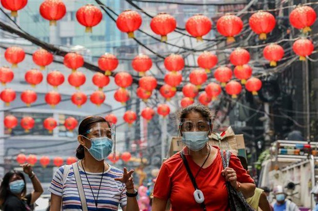 People wearing face masks pass by lanterns at Chinatown in the Philippines' Manila in February 2021. (Photo: Xinhua/VNA)