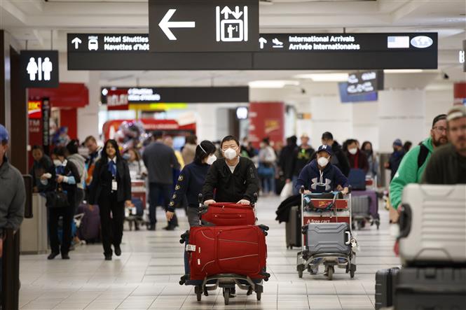  Hành khách đeo khẩu trang phòng lây nhiễm Covid-19 tại sân bay ở Toronto, Canada. Ảnh: AFP/TTXVN