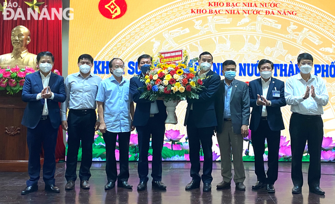 Chairman of the municipal People's Committee Le Trung Chinh (fourth, right) presenting a basket of flowers to congratulate the city's financial sector on completing its budget collection and expenditure tasks in 2021. Photo: M. QUE  