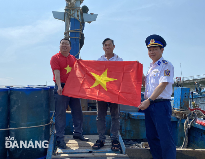 Anh Nguyễn Phương Bình (giữa) đón nhận cờ Tổ quốc trên tàu cá của mình do Vùng Cảnh sát biển 2 trao tặng năm 2020. Ảnh: LÊ VĂN THƠM