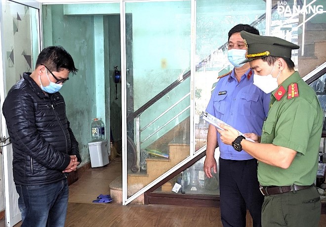 A police officer read a court decision to detain Nguyen Van Minh Tho (left) for facilitating illegal immigration into Viet Nam. L.H