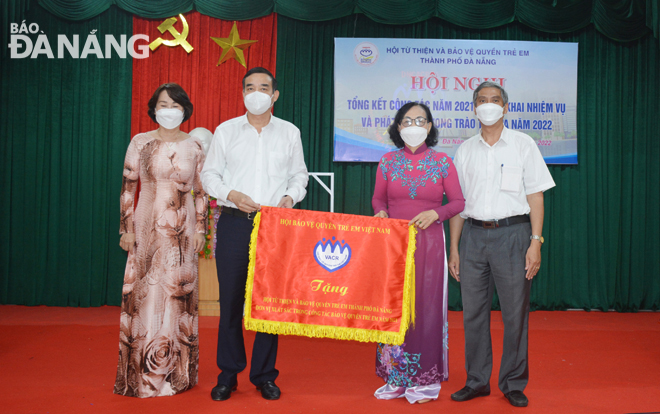 Da Nang People's Committee Chairman Le Trung Chinh (second, left) presenting an emulation flag from the Central Viet Nam Association for Protection of Child's Rights to the Da Nang Association of Charities and Children's Rights Protection in recognition of its leading role in the protection of children's rights in 2021