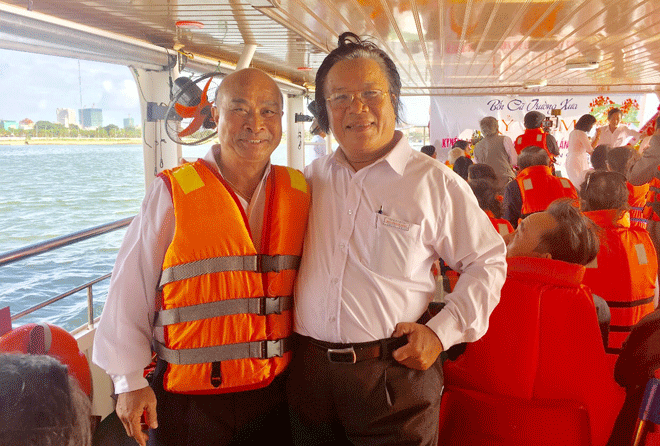 Ông Đặng Hòa (bên phải) chụp ảnh cùng du khách trên thuyền du lịch.  (Ảnh chụp thời điểm không có Covid-19)(Ảnh: Nhân vật cung cấp)