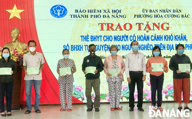 Chủ tịch UBND phường Hòa Cường Bắc Trà Thanh Hải (thứ 3, phải sang) trao thẻ bảo hiểm y tế cho người dân có hoàn cảnh khó khăn. Ảnh: N.Q