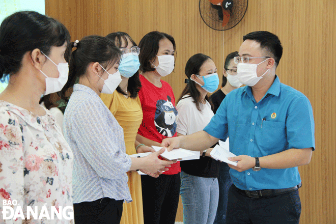 Hai Chau District Labour Confederation Chairman Lu Trong Phuong (in the blue shirt) handing cash assistance to local trade union members. Photo: LAM PHUONG