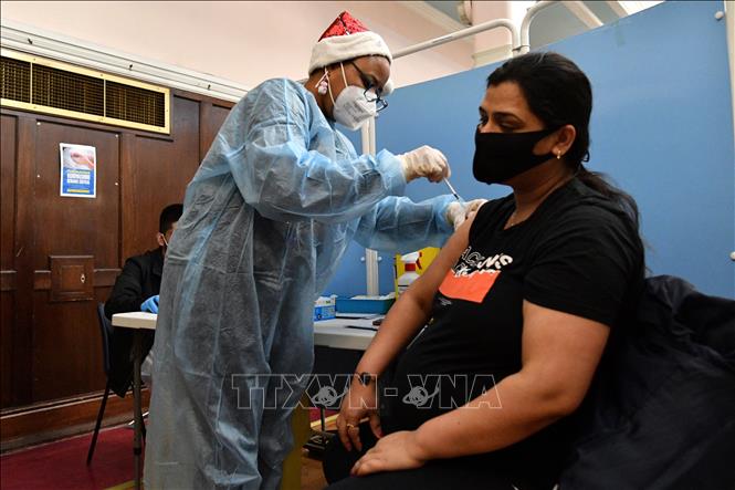 Nhân viên y tế tiêm vaccine phòng Covid-19 cho phụ nữ mang thai tại London, Anh, ngày 25-12-2021. Ảnh: AFP/TTXVN