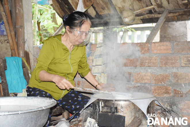 In order to have delicious cakes, Ms. Tran Thi Luyen often rotates her hands while rolling the rice paper on the fire. Photo: D.H.L