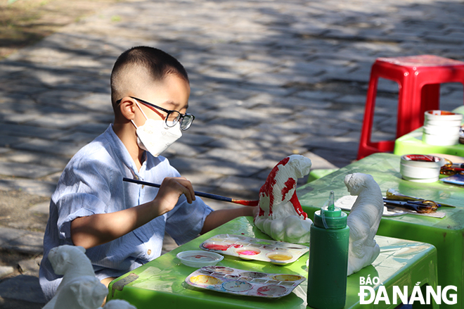 A kid painting colour on his plaster statue