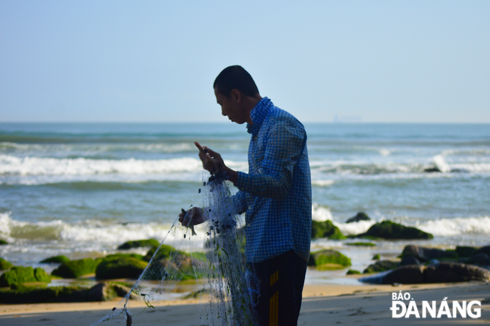  A Nam O fisherman removes fish from a net. 