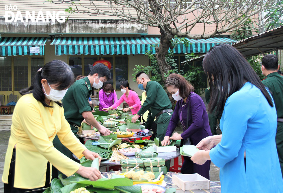 Women and border guard soldier wrapping 'banh chung' (square glutinous rice cakes).