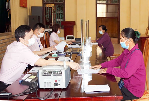 Các đối tượng chính sách ở xã Phù Linh, huyện Sóc Sơn, Hà Nội, đến Điểm giao dịch của Ngân hàng chính sách xã hội tại trụ sở UBND xã làm thủ tục, nhận vốn vay. (Ảnh: Vietnam+)