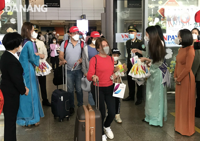 Đại diện lãnh đạo Sở Du lịch thành phố, Hãng hàng không Vietjet Air tặng hoa, quà chúc mừng những vị khách đầu tiên đến Đà Nẵng. Ảnh: M.QUẾ