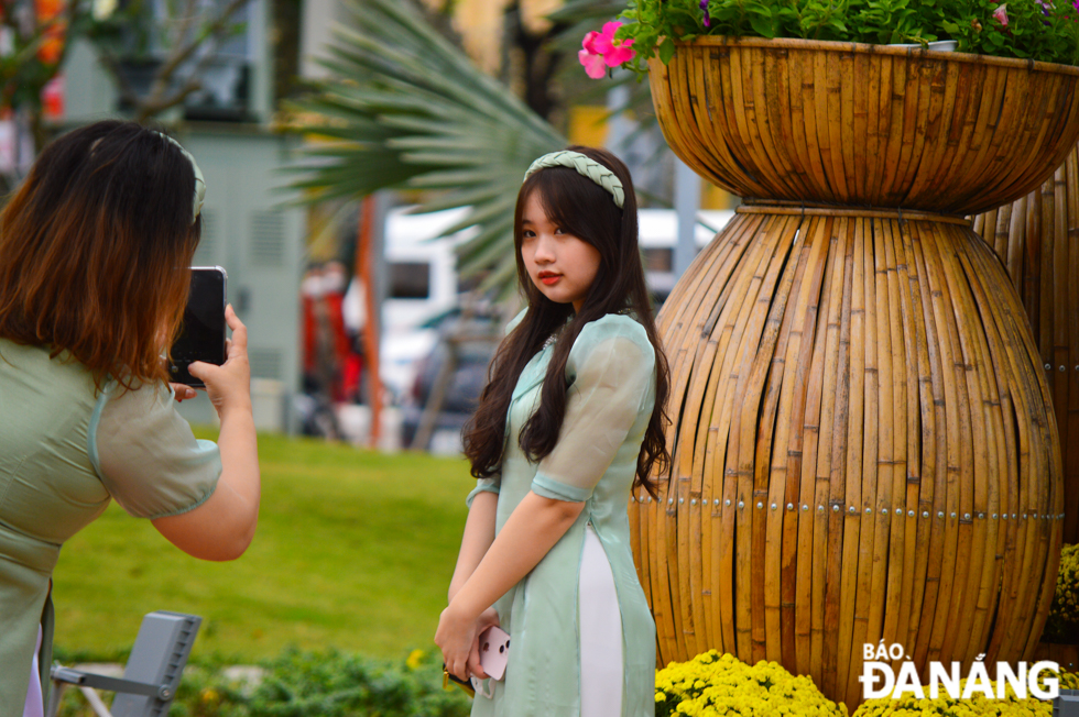 A young women posing a souvenir photo with floral miniature scenes.