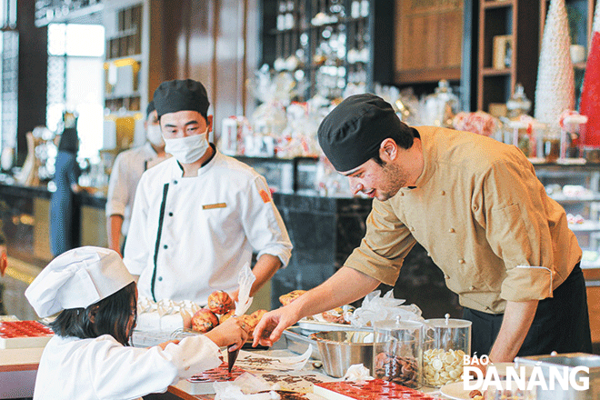 Victor Ceano Savall (first right) who has been settled in Da Nang for 8 years has considered the city to be his second home. IN THE PHOTO: Victor teaching his students to make chocolate. Photo: THU HA