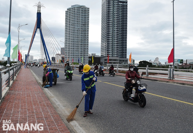 Công nhân Công ty CP Môi trường Đô thị Đà Nẵng vệ sinh cầu Sông Hàn trong sáng 4-2. Ảnh: HOÀNG HIỆP