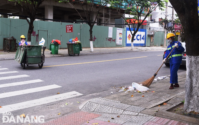 Công nhân Xí nghiệp môi trường Hải Châu vệ sinh và thu gom rác trên tuyến đường Phan Đình Phùng. Ảnh: HOÀNG HIỆP