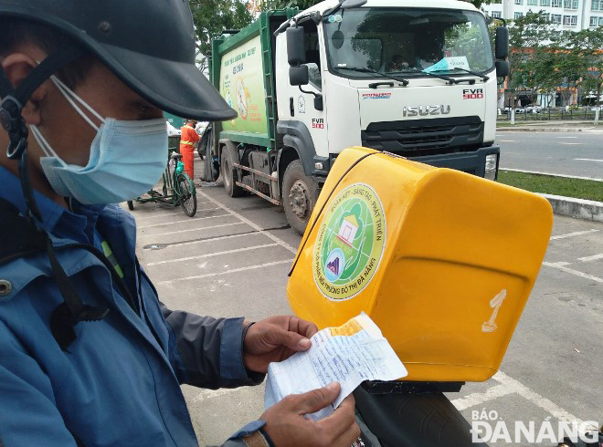 Workers check the list of residential sites where COVID-19 patients stay in order to make preparations for collecting domestic garbage. Photo: HOANG HIEP