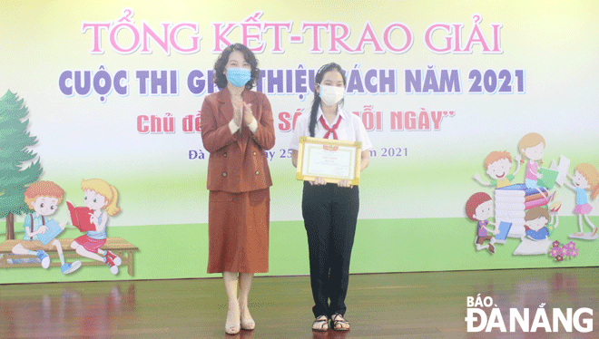Deputy Director of the municipal Department of Culture and Sports Nguyen Thi Hoi An presenting the first prize at the ‘Reading books every day’ contest to Dau Ha Nhi, a 7th grader from the Tran Quang Khai Secondary School.