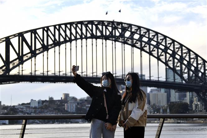 Du khách chụp ảnh lưu niệm tại khu vực Cầu Cảng Sydney, Australia. Ảnh: AFP/TTXVN