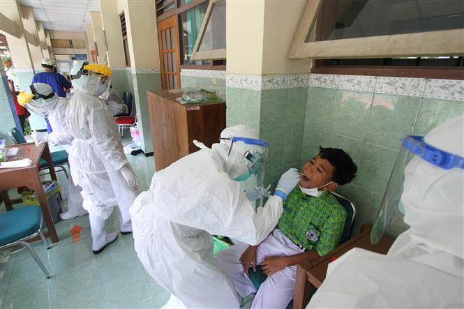 Nhân viên y tế lấy mẫu xét nghiệm Covid-19 cho học sinh tại Java, Indonesia. Ảnh: AFP/TTXVN