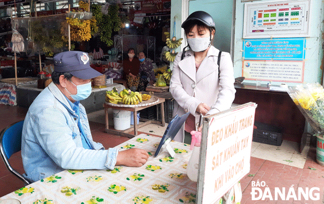 Patrons are required to use a QR code for COVID-19 safe check-in to the Tam Thuan Wet Market in Thanh Khe District as well as disinfect their hands before entering this venue. Photo: Xuan Dung