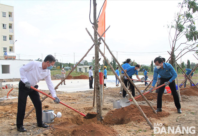 1.	Trưởng Ban Dân vận Thành ủy Lê Văn Trung (bìa trái), Chủ tịch Liên đoàn Lao động thành phố Nguyễn Duy Minh (bìa phải) trồng cây xanh. Ảnh: L.P