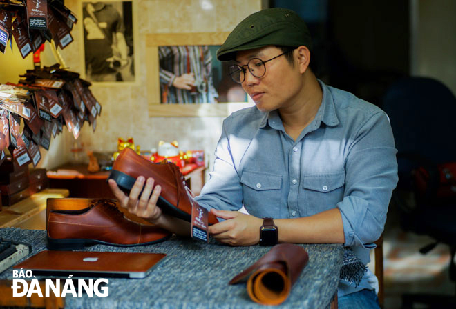 Anh Lê Như Thám (SN 1991), chủ cửa hàng RAM Leather (phường Thanh Bình, quận Hải Châu) bên sản phẩm giày da tâm đắc. Ảnh: TIỂU YẾN