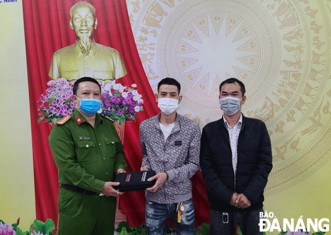 Mr. Huynh Duc Tri (right) and a representative of Phuoc Ninh ward police return the property to Mr. Nguyen Phi Anh (middle). Photo: L.H