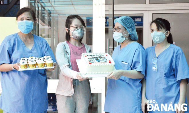 Một bệnh nhân mắc Covid-19 được điều trị khỏi bệnh (thứ hai, trái sang) tặng bánh  cho những người thầy thuốc tại Bệnh viện Đà Nẵng. Ảnh: LÊ HÙNG