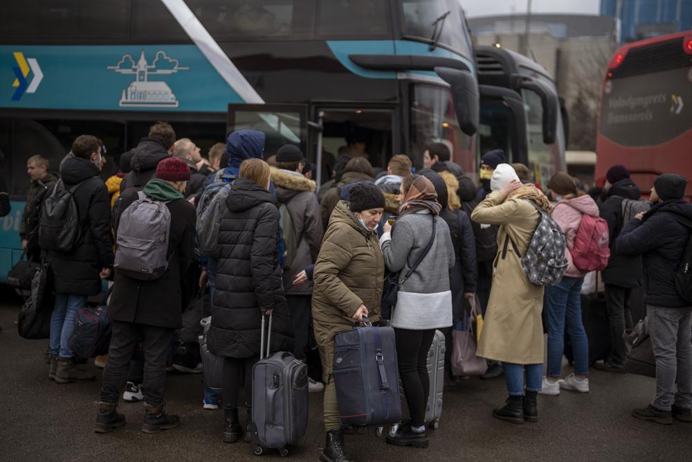Người dân Ukraine lên xe buýt rời thủ đô Kiev. Ảnh: AP