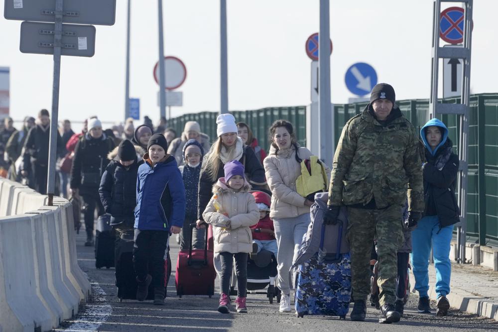 Một lính biên phòng Ba Lan hỗ trợ người tị nạn Ukraine khi họ vừa qua cửa khẩu Korczowa ngày 26-2. Ảnh: AP