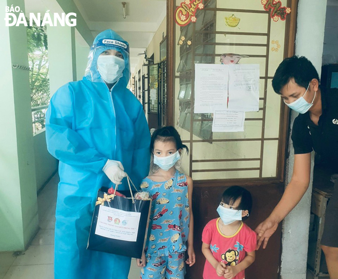 Senior Lieutenant Vo Van Quy from the Phu Loc Border Guard Station (left) presenting a gift to children at a designated quarantine site at the second campus of the Da Nang University of Physical Education and Sports in Thanh Khe District. 