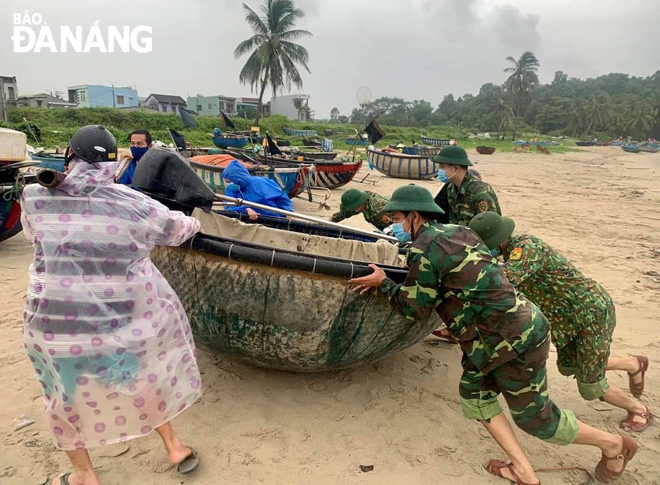 Da Nang border guards helping local fishermen pull a coracle boat ashore in preparation for the approaching storm in 2021 